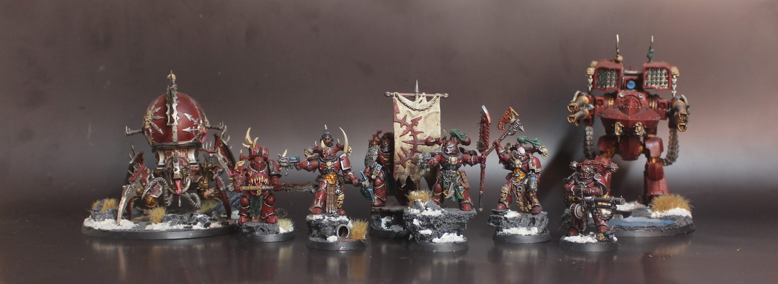 A war-band of Chaos Space Marine miniatures in oxblood armour and tarnished brass