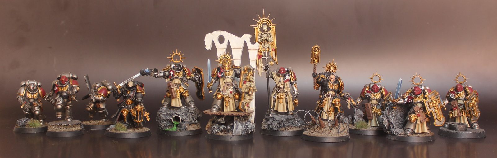 A parade line of loyalist Space Marine miniatures in silver-grey armour and gold robes